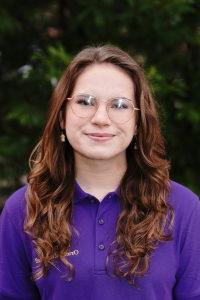 Photo of Kat Hughes wearing a purple Orientation Leader polo shirt.